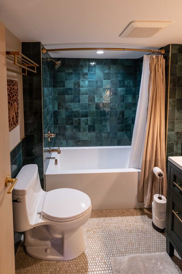Bathroom with deep green tile around the tub and shower