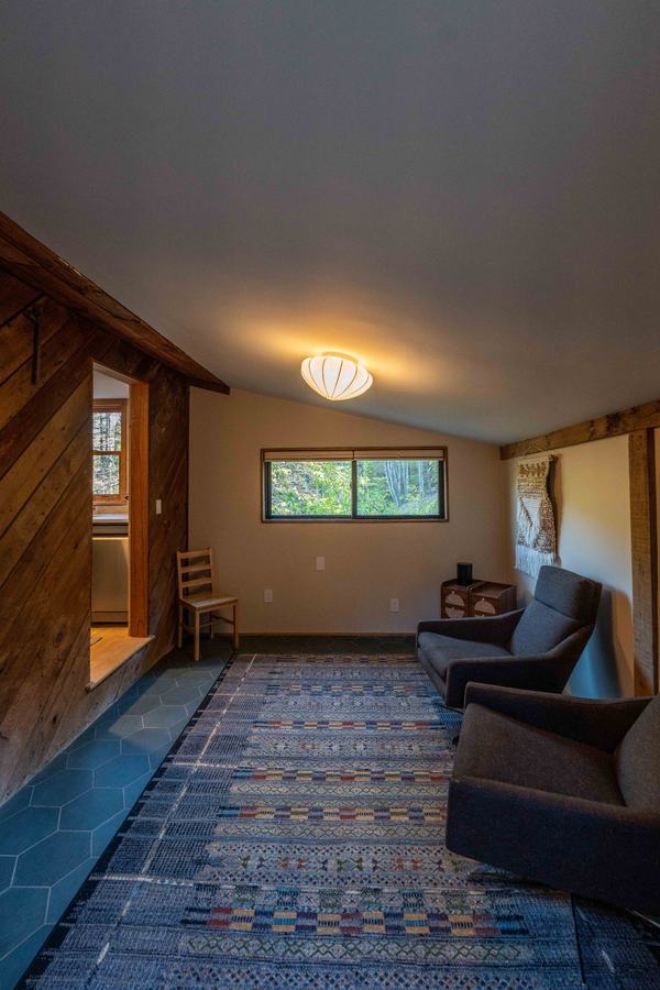 Den with two gray swivel chairs, patterned rug and window to the woods
