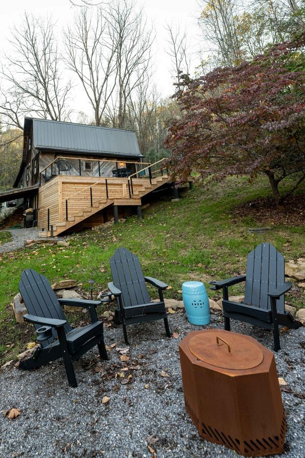 Adirondack chairs around the fire pit below the cabin