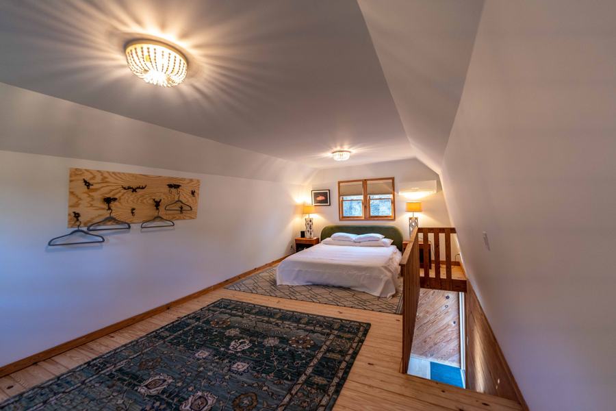 Loft bedroom with queen bed, green headboard and two lamps