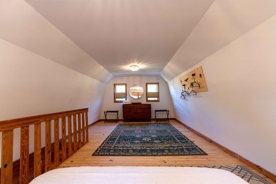End of the loft with dresser, round mirror and luggage racks